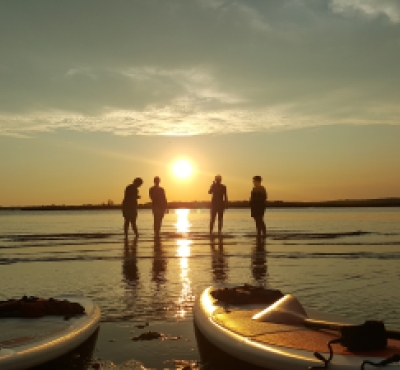 Group on CT shoreline during sunset with kayaks in foreground