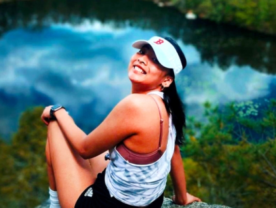A woman enjoying the view of a pond while sitting on a scenic overlook.